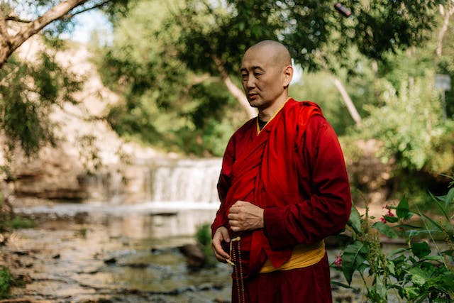 tibetan monk walking in nature at the water's edge